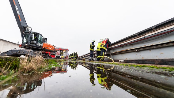 Die Feuerwehr pumpt ein mit Wasser vollgelaufenes Binnenschiff, dass an einer Keilmauer auf dem Dortmund-Ems Kanal in  Spelle liegt mit insgesamt vier Pumpen leer. © dpa-Bildfunk Foto: Guido Kirchner
