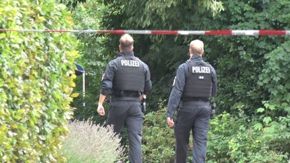 Zwei Polizisten gehen hinter einer Absperrung lang. © NWM 