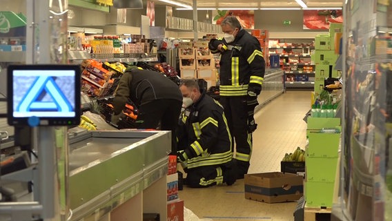 Einsatzkräfte der Feuerwehr zwischen Bananenkisten. © dpa/Nord-West-Media 