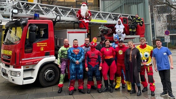 Höhenretter der Feuerwehr Osnabrück stehen als Superhelden verkleidet vor einer Drehleiter. © NDR Foto: Andreas Gervelmeyer