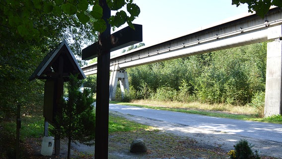 Ein Holzkreuz steht vor einer Transrapid-Strecke. © NDR Foto: Hedwig Ahrens