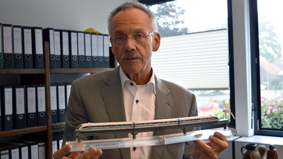 Samtgemeindebürgermeister Karl-Heinz Weber hält ein Transrapid-Modell in den Händen. © NDR Foto: Hedwig Ahrens