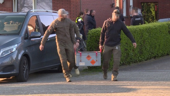 Spezialkräfte der Polizei tragen eine Kiste mit sichergestellter Munition aus einem Wohnhaus in Twist. © Nord-West-Media TV 
