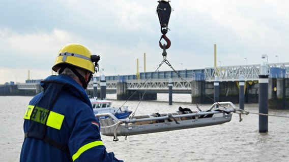 Ein Mitarbeiter des THW lässt eine Trage ins Wasser. © NDR Foto: Andreas Barnickel