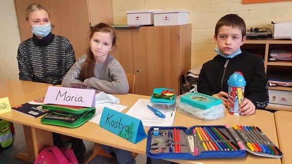 Eine Frau sitzt neben einem aus der Ukraine geflüchteten Mädchen in einem Klassenraum. © NDR Foto: Susanne Schäfer