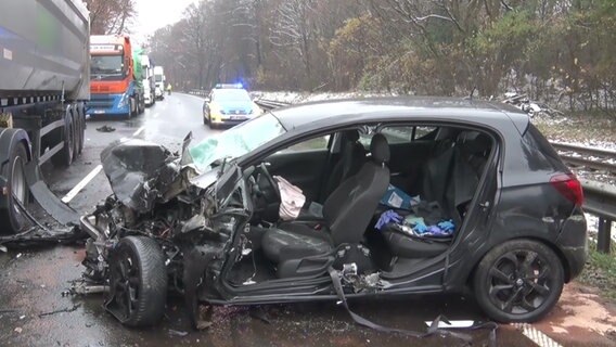 Nach einem Unfall in Haselünne steht ein stark beschädigtes Auto neben einem Lkw auf einer Straße. © Nord-West-Media TV 