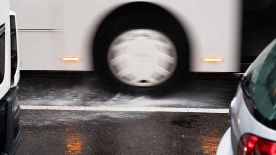 Reifen von einem Bus peitschen Wasser auf einer Fahrbahn hoch. © picture alliance/dpa/Friso Gentsch Foto: Friso Gentsch