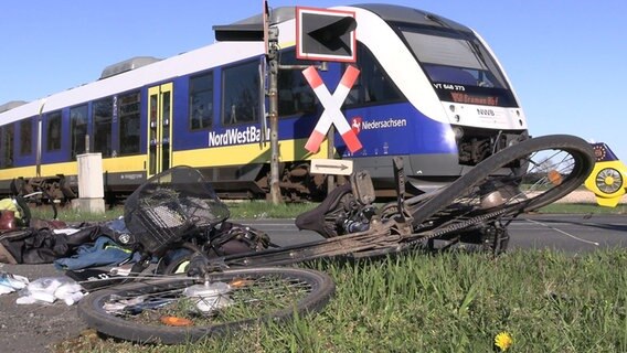 Ein Fahrrad liegt an einem Bahnübergang neben einem Regionalzug. © dpa-Bildfunk/Nord-West-Media TV 