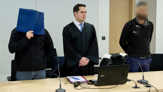 Zwei Angeklagte stehen zusammen mit dem Rechtsanwalt Thilo Schäck im Landesgericht nebeneinander. © dpa Foto: Philipp Hülsmann