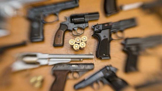 Kurzwaffen (Pistolen und Revolver) und Munition liegen auf einem Tisch in der gesicherten Asservatenkammer der Waffenbehörde des Landkreises Osnabrück. © dpa-Bildfunk Foto: Friso Gentsch