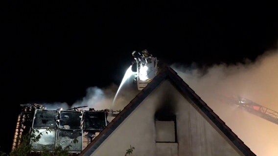 Einsatzkräfte der Feuerwehr löschen einen Brand von einer Drehleiter. © Nord-West-Media TV 
