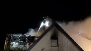 Einsatzkräfte der Feuerwehr löschen einen Brand von einer Drehleiter. © Nord-West-Media TV 