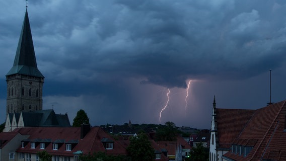 Dunkle Gewitterwolken und Blitze sind gleichzeitig in Osnabrück (Niedersachsen) am Himmel zu sehen. © dpa-Bildfunk Foto: Friso Gentsch