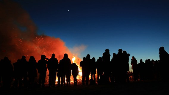Mehrere Menschen stehen um ein Osterfeuer herum. © dpa - Bildfunk Foto: Marcel Kusch