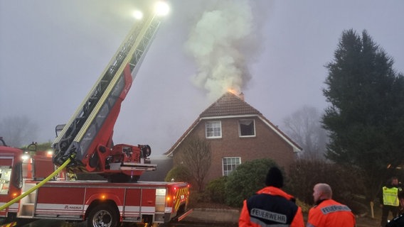 In Oxstedt steht ein Einfamilienhaus in Flammen. Der Rauch steigt aus dem Gebäude. Die Feuerwehr steht mit einer Drehleiter davor. In Oxstedt steht ein Einfamilienhaus in Flammen. Der Rauch steigt aus dem Gebäude. Die Feuerwehr steht mit einer Drehleiter davor. © Polizeiinspektion Cuxhaven Foto: Pressestelle Polizei Cuxhaven