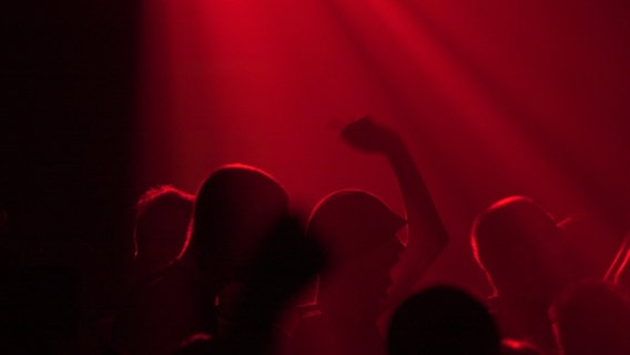 Besucher einer Party tanzen im Scheinwerferlicht. © picture-alliance / dpa | Arne_Dedert Foto: picture-alliance / dpa | Arne_Dedert