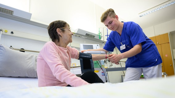 Ein Pflegefachmann legt einer Patientin ein Blutdruckmessgerät um den Arm. © picture alliance/dpa | Robert Michael Foto: Robert Michael
