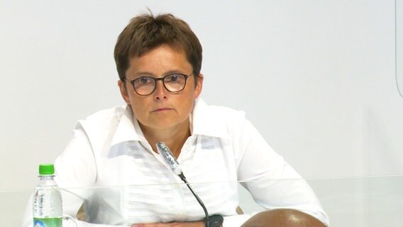 Government spokeswoman Anke Poerksen sits at a lectern.  