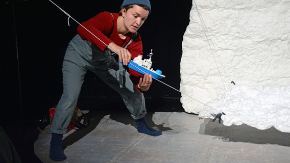 Bei einem Theaterstück zum Forschungsschiff "Polarstern" hält ein Mensch ein Spielzeugboot in Händen. © NDR Foto: Jutta Przygoda