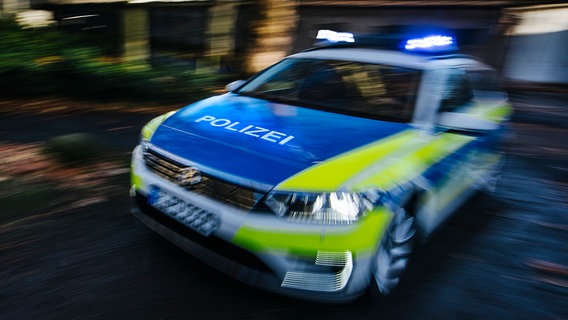 Ein mit Bewegungsunschärfe abgelichtetes Polizeiauto fährt mit Blaulicht eine Straße entlang. © NDR Foto: Julius Matuschik
