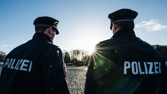 Zwei Polizisten stehen nebeneinander auf einer Straße. © NDR Foto: Julius Matuschik