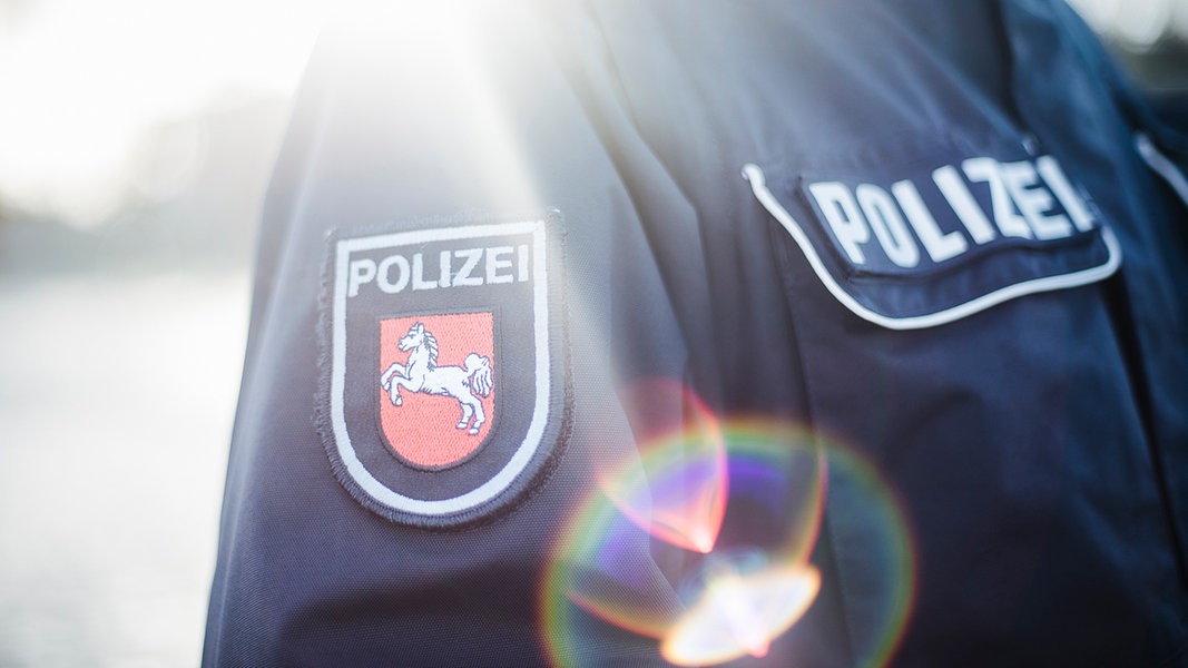 Auf dem mit Gegenlicht fotografiertem Jackenärmel einer Polizeiuniform ist das niedersächsischen Wappen aufgenäht.