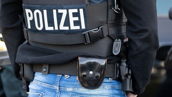 Ein Polizist von hinten, der eine Schutzweste und eine Pistole trägt. © picture alliance / Fotostand Foto:  Fotostand / Gelhot