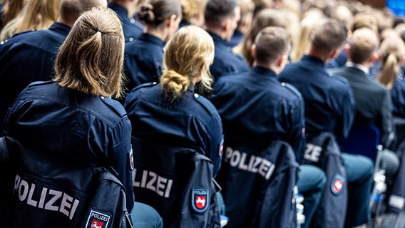 Polizistinnen und Polizisten des Bachelorstudienjahrgangs der Polizeiakademie Niedersachsen sitzen bei ihrer Abschlussfeier in der Swiss Life Hall. © picture alliance/dpa | Moritz Frankenberg Foto: Moritz Frankenberg