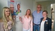 Vermieterfamilie Fricke und Gina Kirchner von der zentralen Stelle für Wohnraumhilfe vor dem Plakat des Projektes Probewohnen. © NDR Foto: Frank Ihben