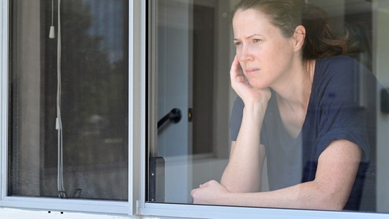 Eine Frau schaut gelangweilt aus dem Fenster ihrer Wohnung. © picture-alliance Foto: Rafael Ben-Ari