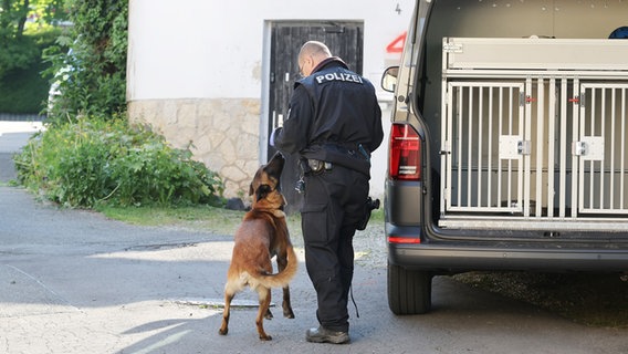 Ein Polizist mit einem Polizeihund bei Durchsuchungen von "Reichsbürger"-Gebäuden. (Themenbild) © Bodo Schackow/dpa Foto: Bodo Schackow/dpa