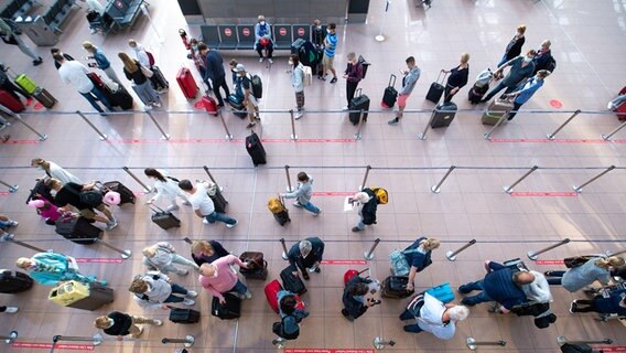 Fluggäste warten in einer langen Schlange vor dem Check-In in einem Flughafen © picturealliance Foto: Jonas Walzberg