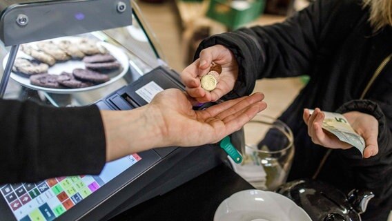 Eine Frau gibt an einer Restaurantkasse Geld in die Hand eines Kassierers. © picture alliance/dpa Foto: Carsten Koall