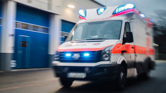 Ein mit Bewegungsunschärfe fotografierter Rettungswagen fährt mit Blaulicht über eine Straße. © NDR Foto: Julius Matuschik