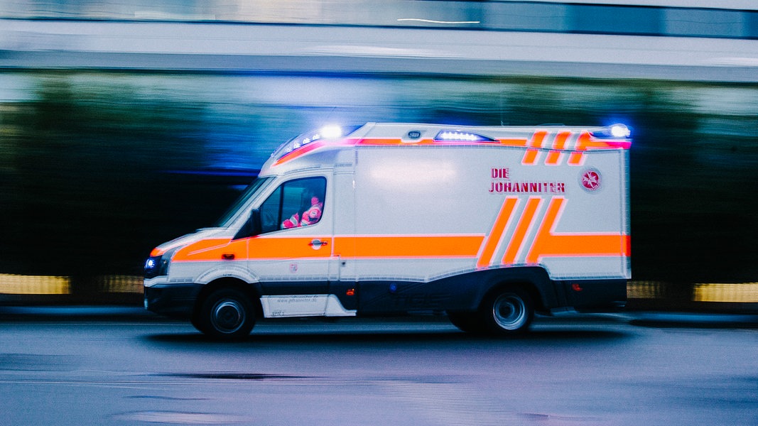 Ein Rettungswagen fährt mit eingeschaltetem Blaulicht über eine Straße.