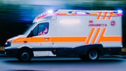 Ein Rettungswagen fährt mit eingeschaltetem Blaulicht über eine Straße. © NDR Foto: Julius Matuschik
