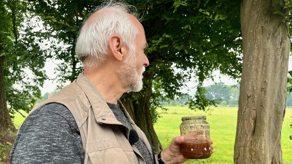 Wolfgang Rozicki schmiert eine Brei aus überreifen Bananen, Zucker und Rotwein an Bäume, um Schmetterlinge anzulocken. © NDR Foto: Marie Stiller
