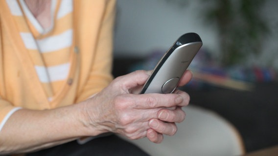 Eine ältere Frau hält ein Telefon in beiden Händen. © picture alliance / Eibner-Pressefoto | Fleig / Eibner-Pressefoto 