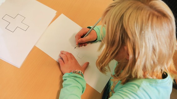 Ein Kind malt ein medizinisches Symbol auf ein Blatt Papier. © picture alliance/dpa | Marcel Kusch Foto: Marcel Kusch