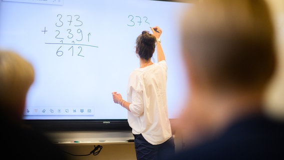 Eine Lehrerin schreibt eine Mathematikaufgabe auf eine digitale Schultafel. © picture alliance/dpa/Julian Stratenschulte Foto: Julian Stratenschulte