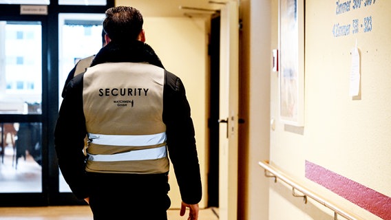 Mitarbeiter einer Sicherheitsfirma gehen den Flur der Flüchtlingsunterkunft in der Bessemerstraße entlang. © picture alliance/dpa | Britta Pedersen Foto: Britta Pedersen