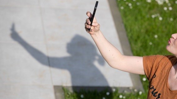 Eine Frau hält ein Smartphone in der Hand und macht ein Selfie. © dpa-Bildfunk Foto: Friso Gentsch