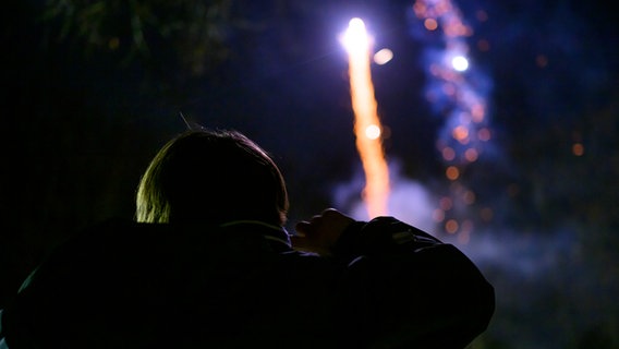 Ein Kind schaut einem Feuerwerk kurz vor Silvester zu und hält sich die Ohren zu. © picture alliance/Kirchner-Media Foto: Christopher Neundorf