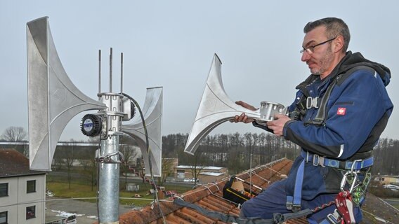 Ein Servicetechniker montiert eine elektronische Sirene auf einem Hausdach. © picture alliance/dpa Foto: Patrick Pleul
