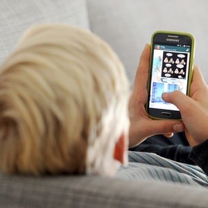 Ein Kind liegt mit einem Smartphone in der Hand auf einem Sofa. © dpa-Bildfunk Foto: Tobias Hase