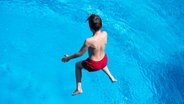 Ein Junge springt in einen Pool im Freibad Kaifu in Hamburg. © dpa-Bildfunk 