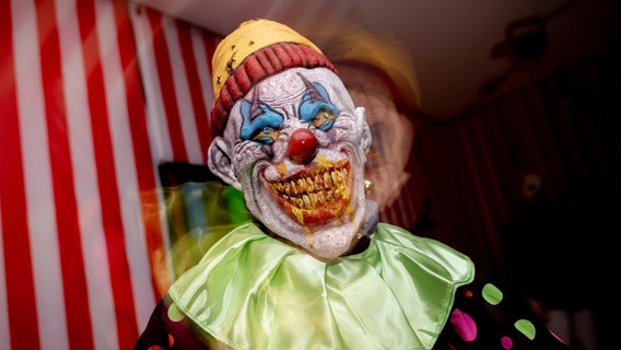 Eine Clownfigur steht in einem Themenbereich der temporären Attraktion "Das Spukhaus 2023" in Wilhelmshaven. © Hauke-Christian Dittrich/dpa +++ dpa-Bildfunk +++ Foto: Hauke-Christian Dittrich