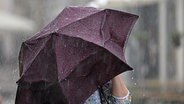 Eine Frau steht unter einem Regenschirm. © picture alliance/dpa | Martin Schutt Foto: Martin Schutt