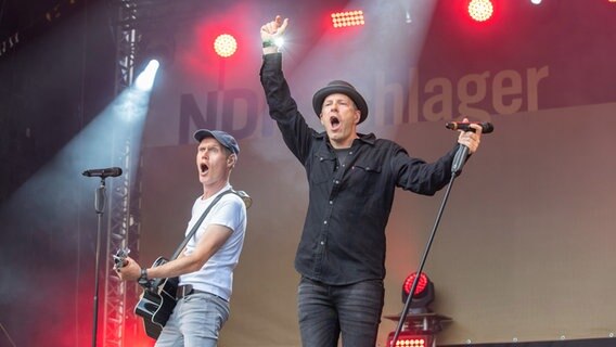 "Die JunX" performen beim Tag der Niedersachsen auf der Bühne, beide Musiker singen lauthals, einer spielt Gitarre. © NDR Foto: Axel Herzig