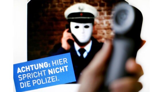 Ein Plakat der Polizei zu sehen, das vor falschen Polizisten warnt. Davor ein Telefonhörer. © dpa-Bildfunk/Martin Gerten/dpa Foto: Martin Gerten